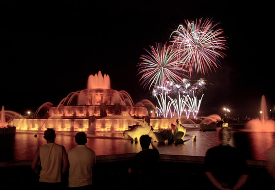 People watching fireworks in the sky at Buckingham Fountain